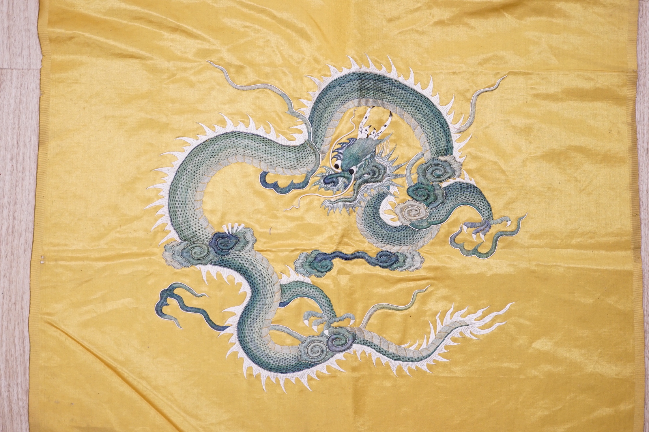 An early 20th century Chinese gold satin panel embroidered with two silk dragons, in couch work, 101cm x 60cm
